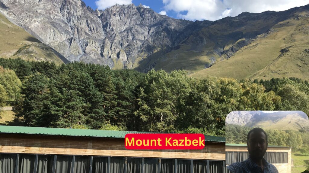 Man taking a picture of Mount Kazbek from a balcony.