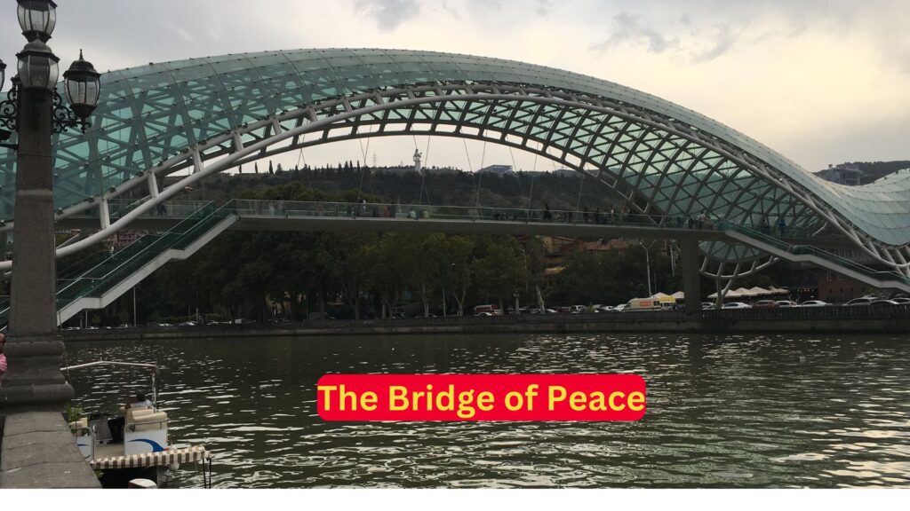 Man standing in front of the Bridge of Peace in Tbilisi, Georgia.