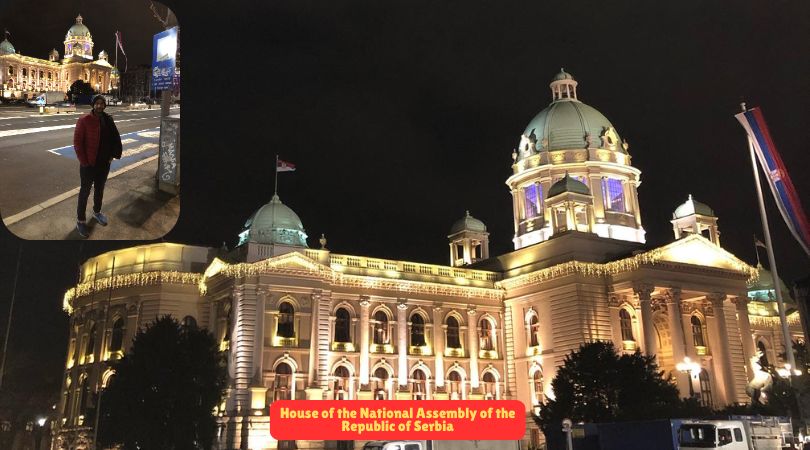 A man standing in front of the House of National Assembly in Belgrade, showcasing its grand architecture.